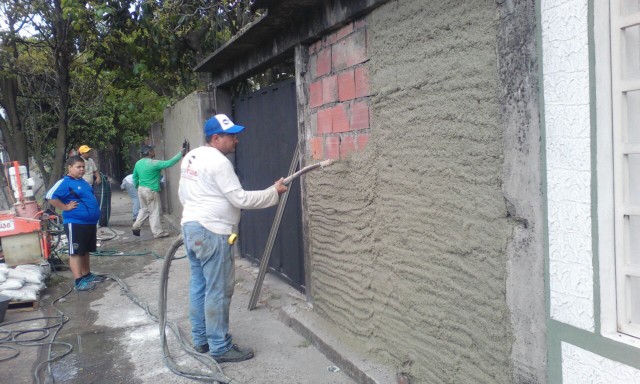 Las cuadrillas trabajan con la revocadora para proyectar la mezcla a usarse en el friso de las paredes de  las viviendas ubicadas en la Marginal del Torbes.